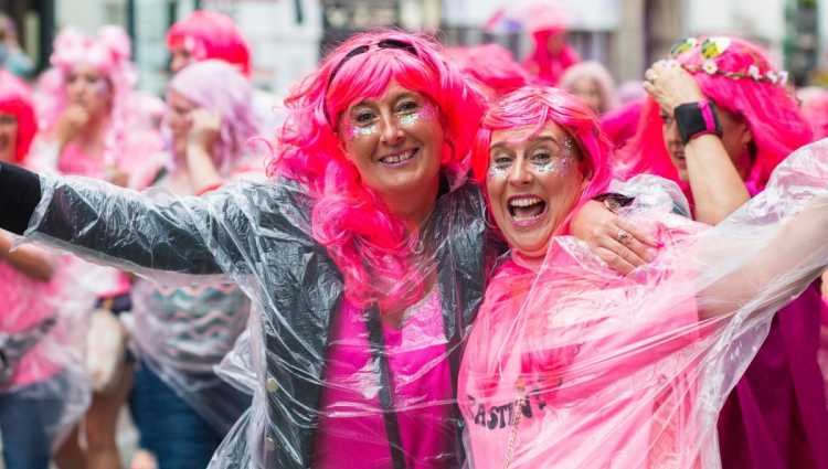 Two supporters wearing pink wigs and glitter with outstretched arms