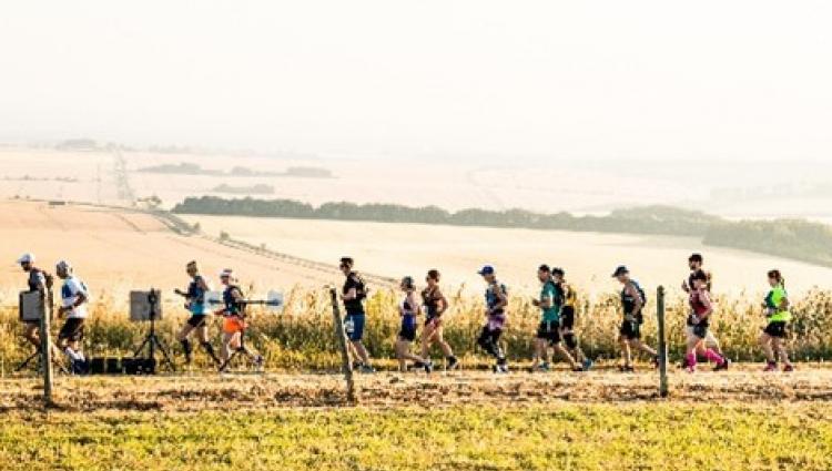 A line of runners in the middle of a sun-baked countryside vale competing in Race to the stones
