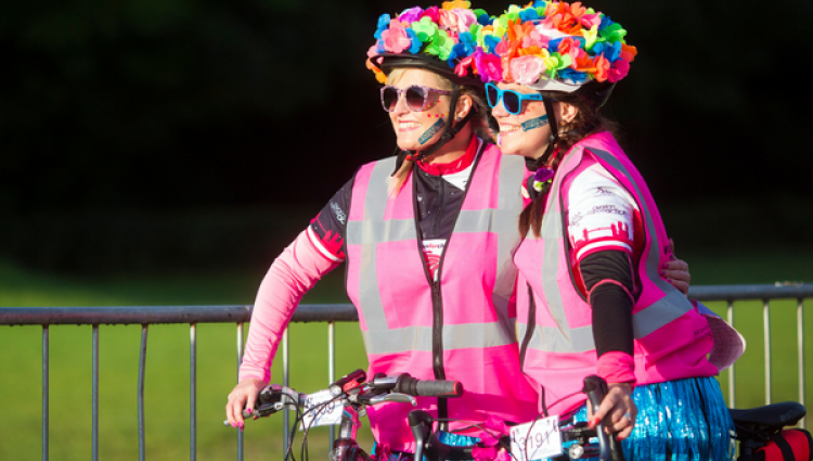 Ride the Night Manchester - Two cyclists smiling wearing helmets decorated with flowers